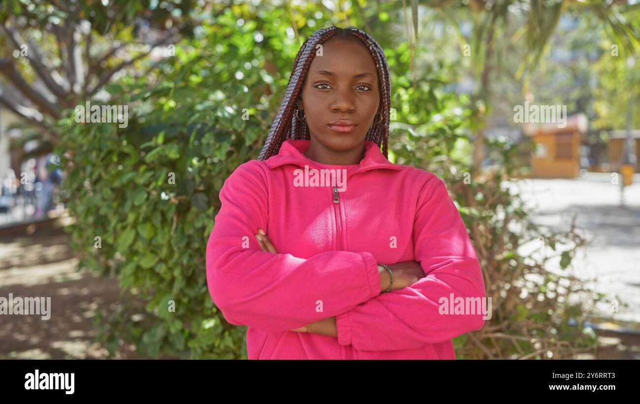 Confident african woman with braids standing arms crossed in a green ...