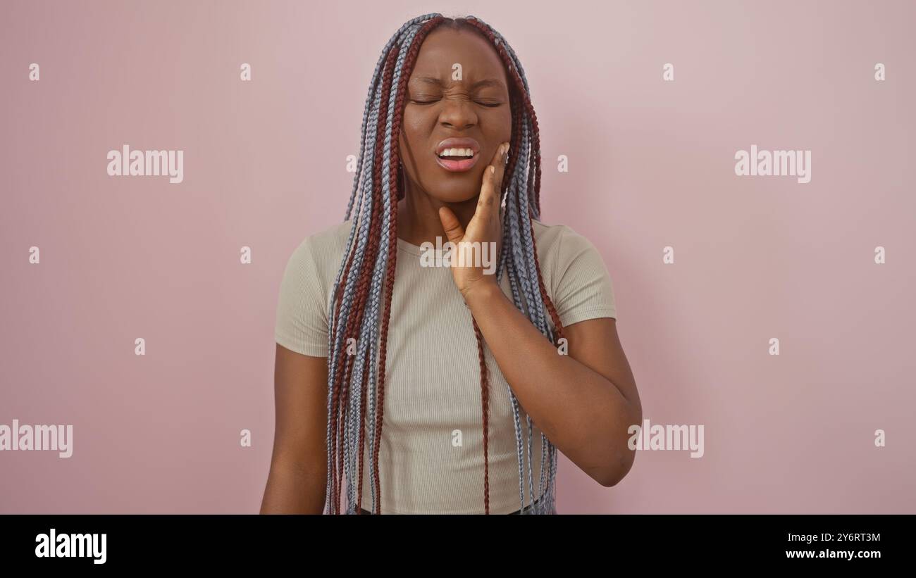 African american woman with braids expressing pain against a pink ...