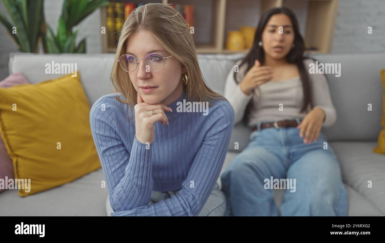 Two women in a living room with one looking contemplative and the other ...