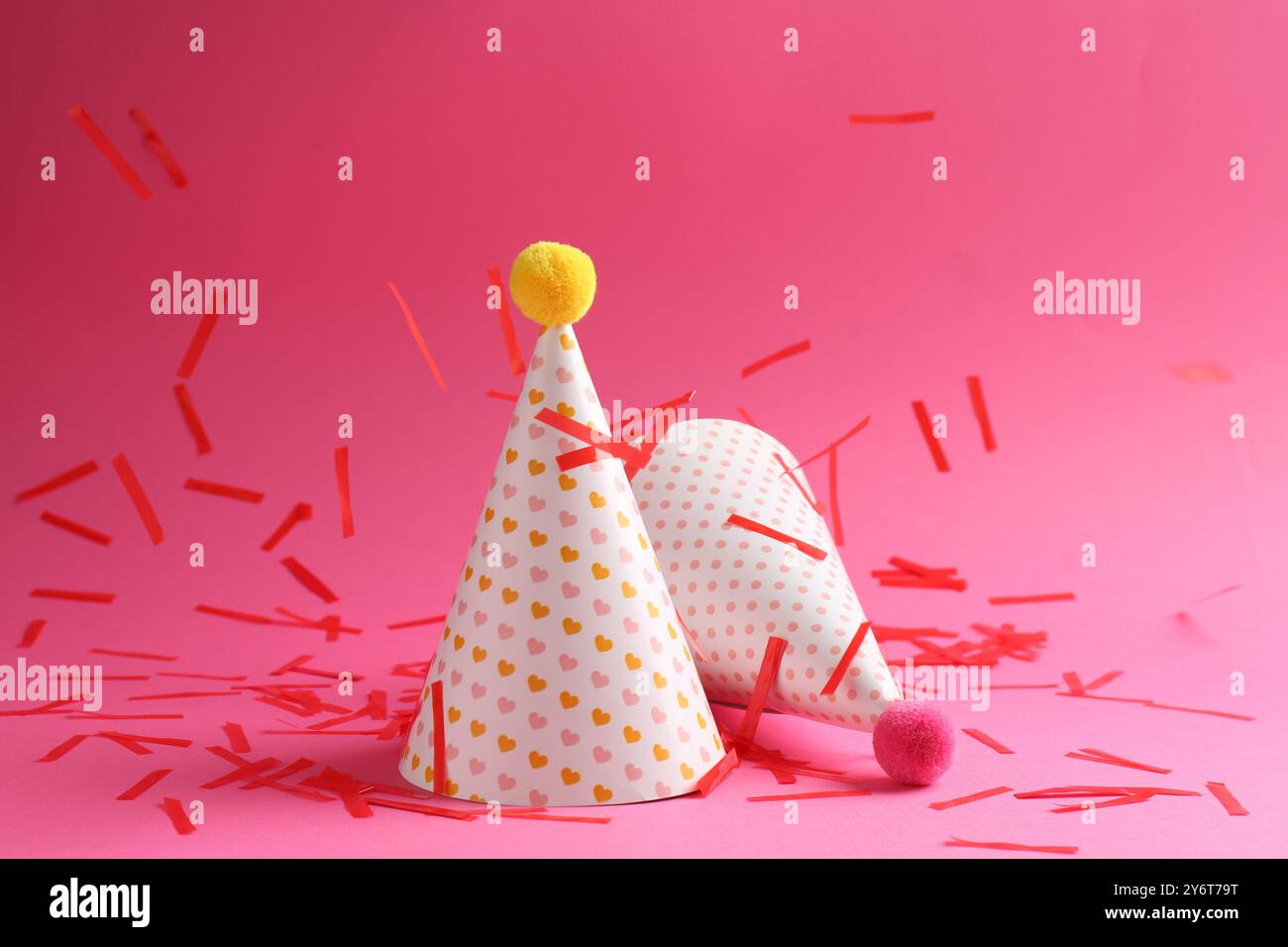Beautiful confetti falling on party hats against pink background Stock ...