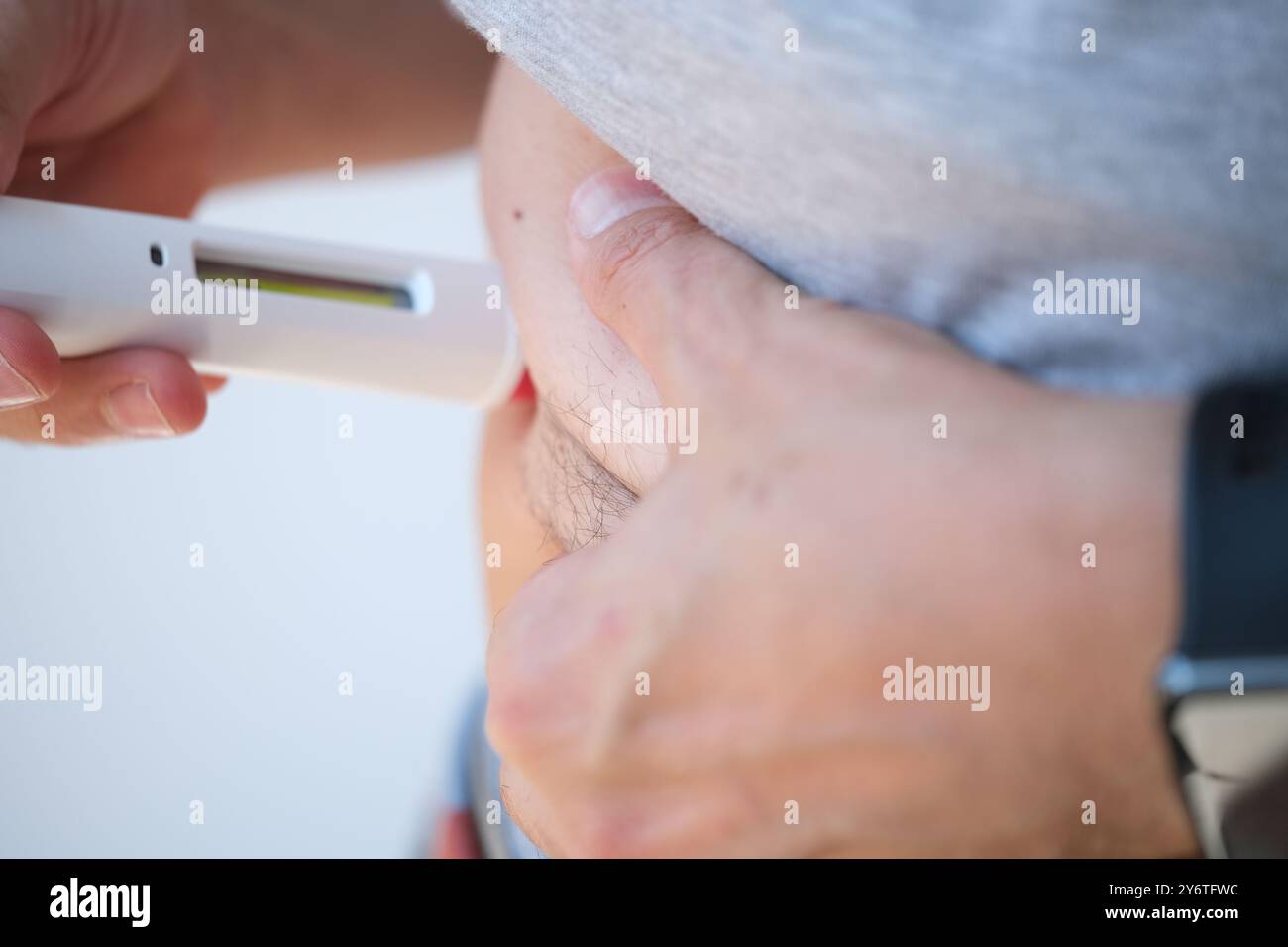 Detail of a man injecting himself in the side abdominal area with a ...