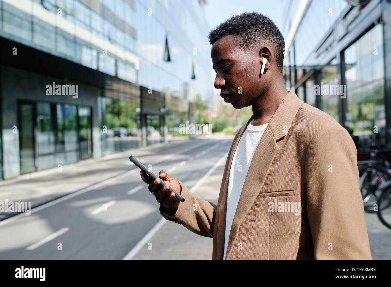 Young Black Manager Using Smartphone While Standing Outdoors Stock Photo