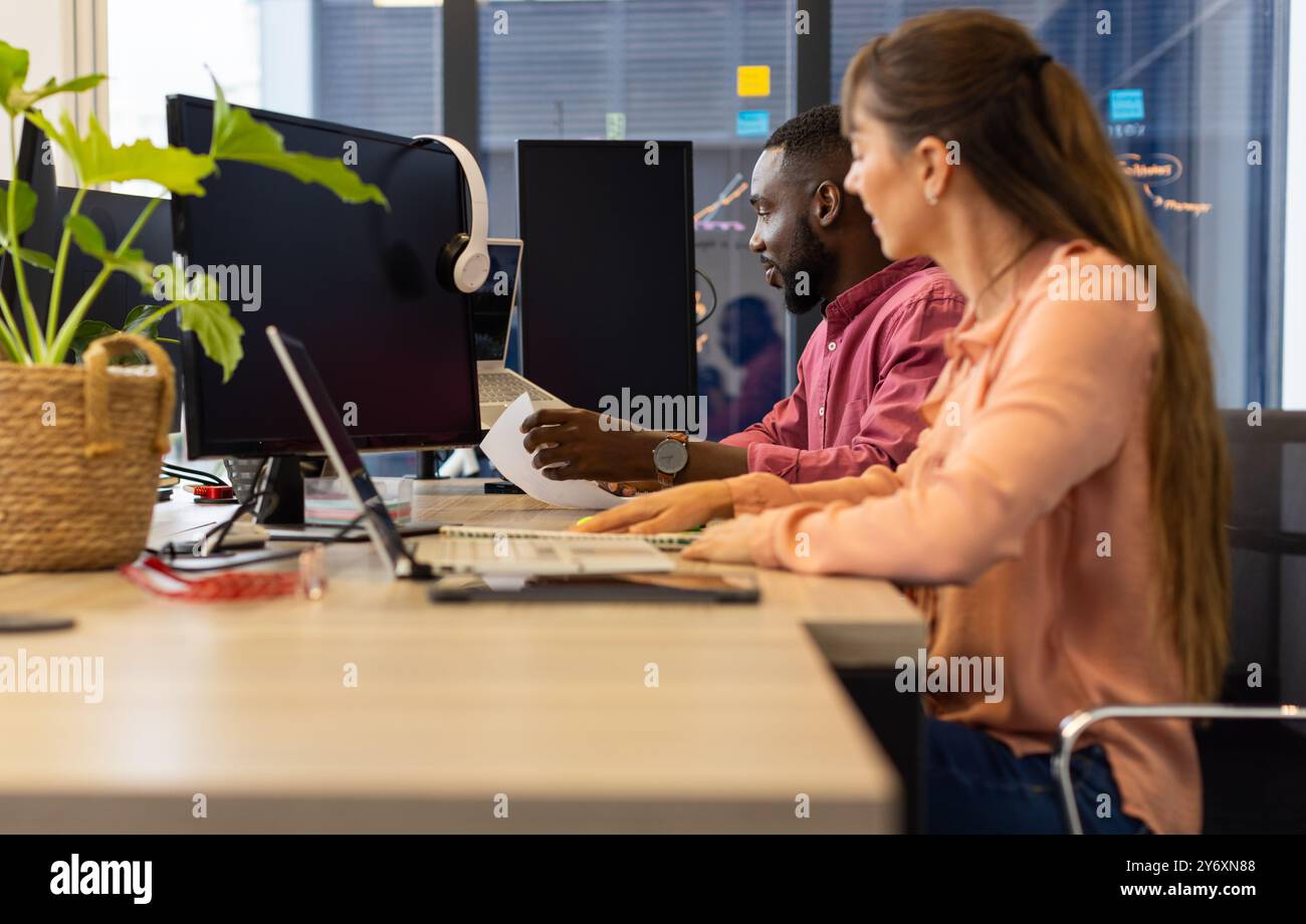 Working in office, colleagues collaborating on project using computers and documents Stock Photo