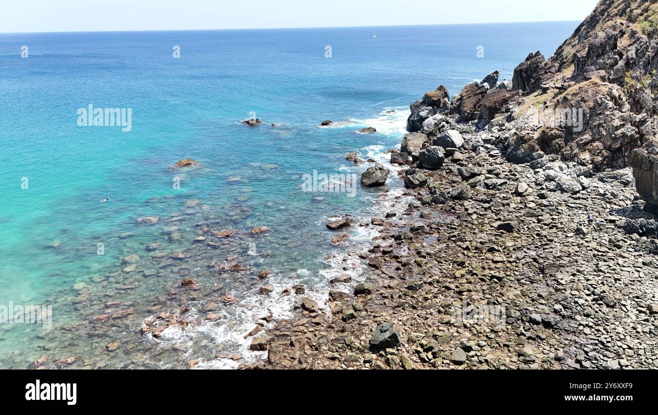 A coastal landscape with clear turquoise waters and rocky shoreline ...