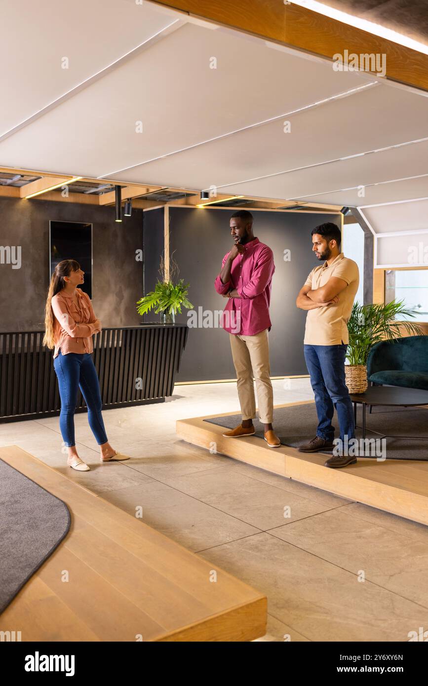 Discussing project ideas, three colleagues standing in modern office space Stock Photo