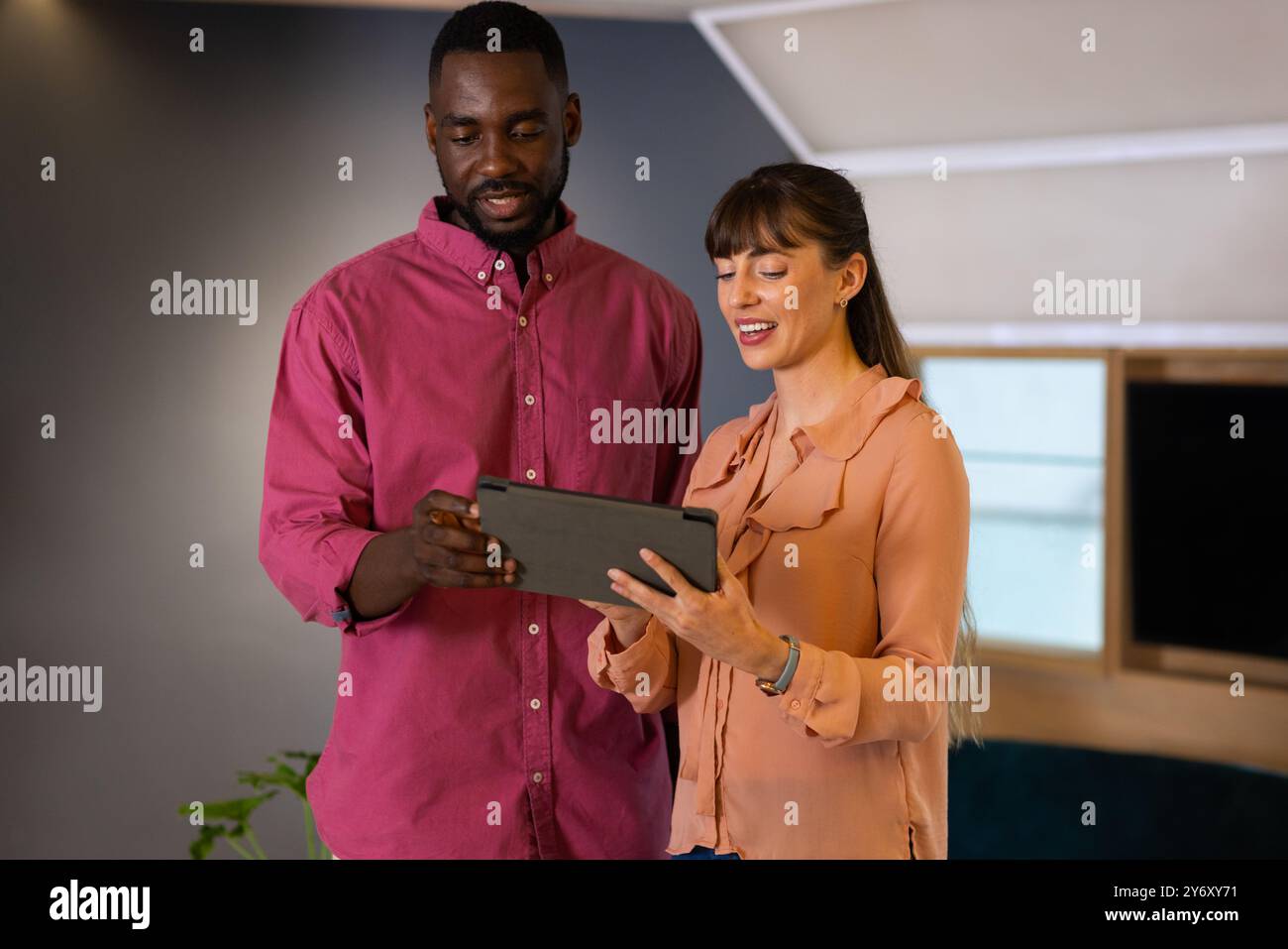 Collaborating on project, colleagues discussing work using digital tablet in office Stock Photo