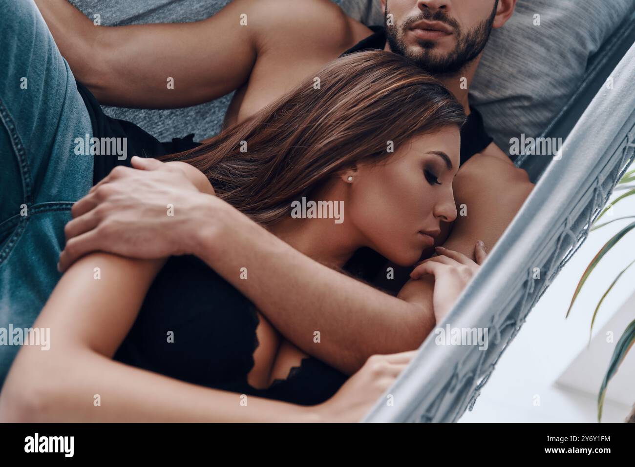 Real love. Top view of beautiful young couple embracing while sleeping in the hammock indoors Stock Photo