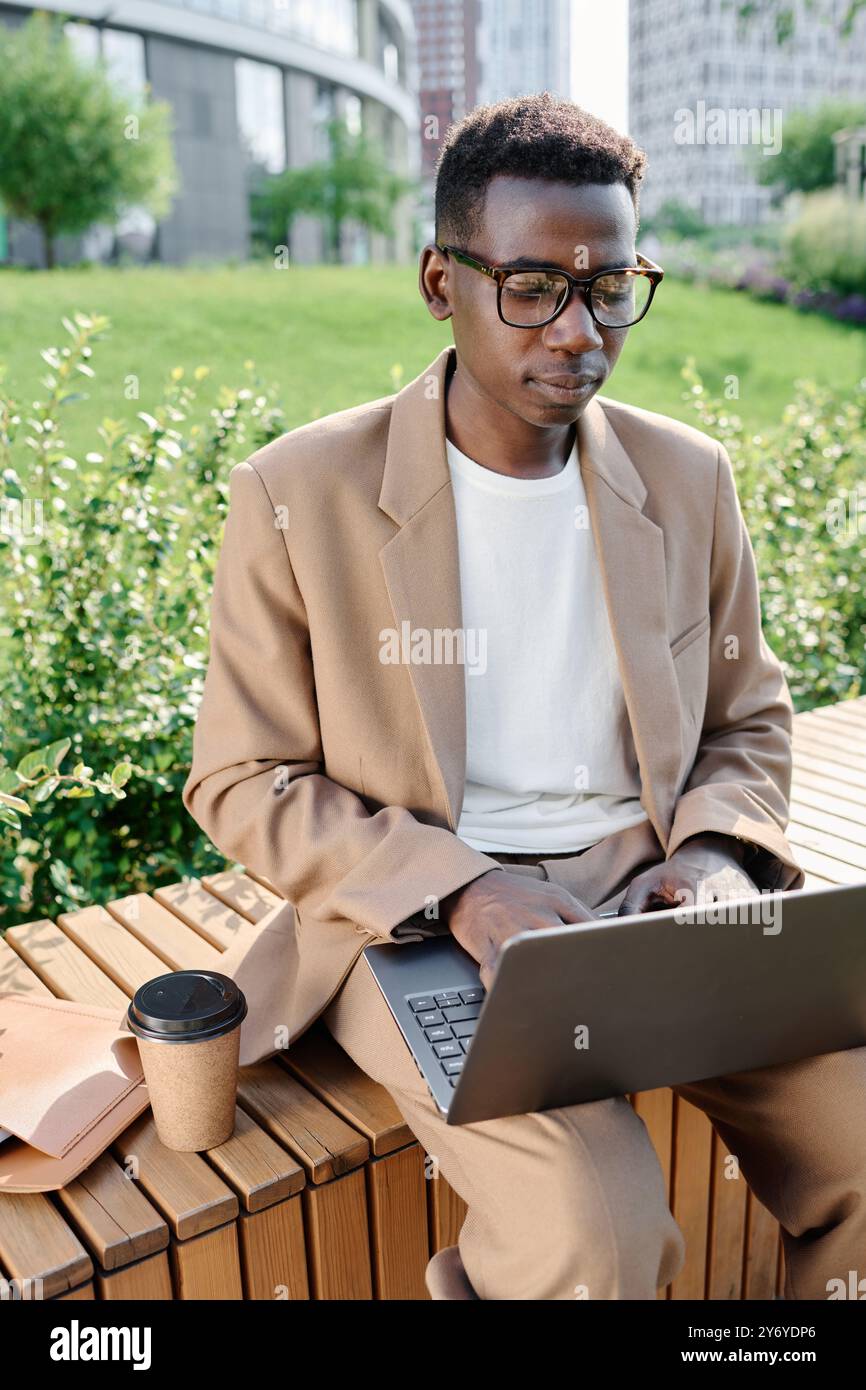 Young Black Man Working On Laptop Outdoors Stock Photo