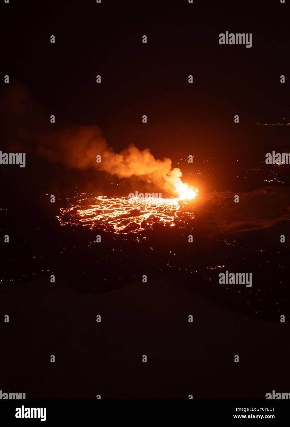 A dramatic night view of an erupting volcano with flowing lava and ...