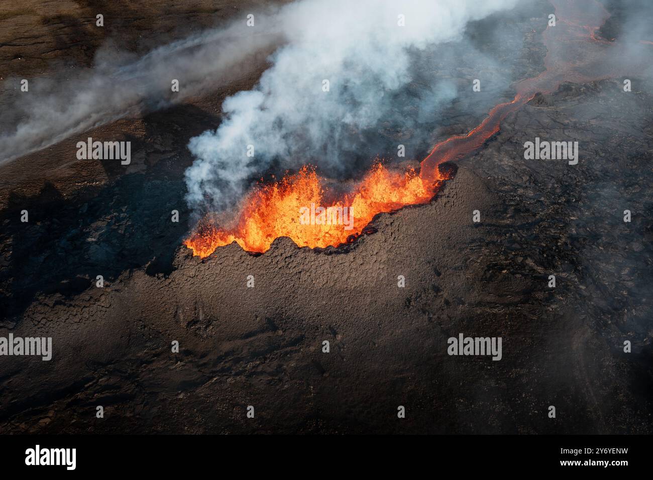 Aerial view of an active volcano erupting with lava flow and smoke in a ...