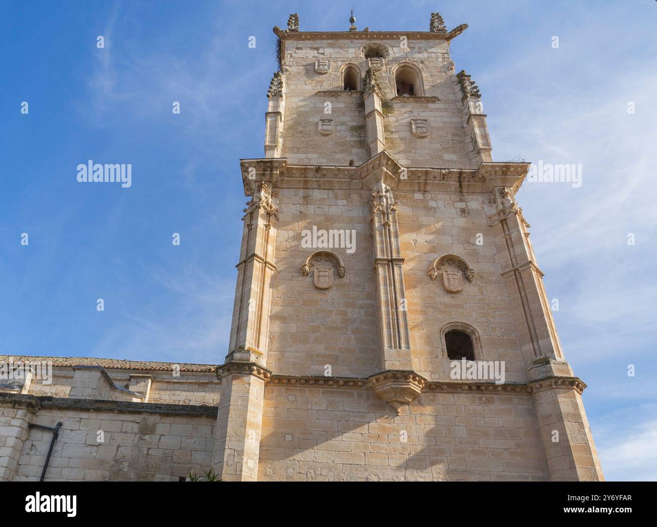 A detailed view of an ancient stone church tower under a clear blue sky ...