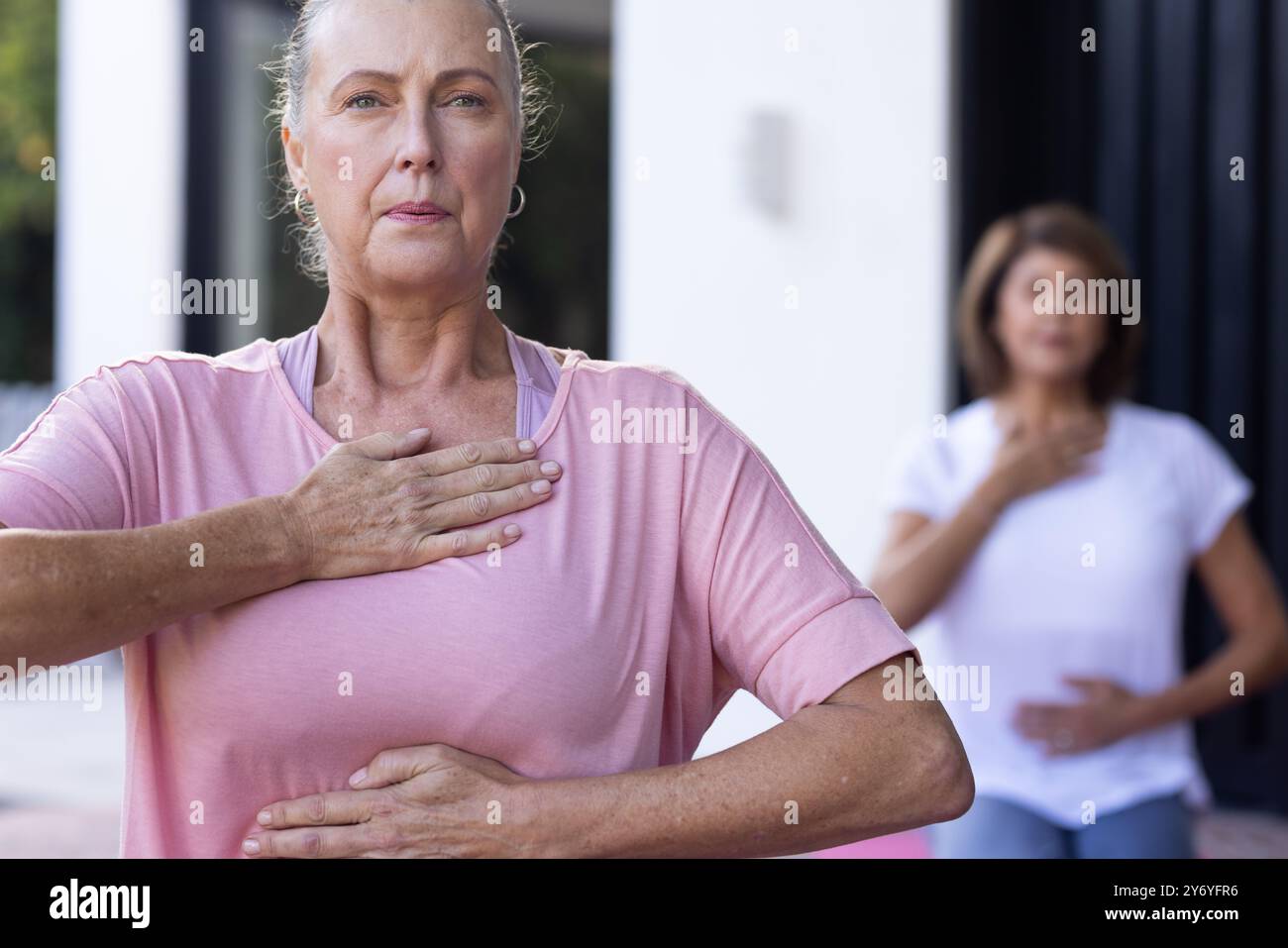 Practicing mindfulness, senior women doing breathing exercises together outdoors, at home Stock Photo