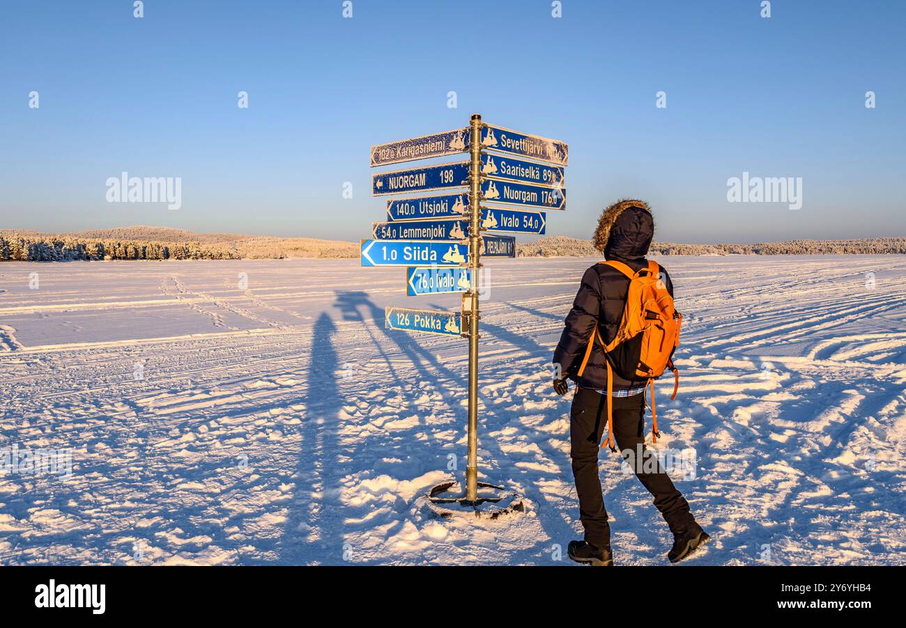 Hikers walking above the snow of the completely frozen and snow-covered Lake Inari in winter, Northern Finland (Lapland, Finland) Stock Photo