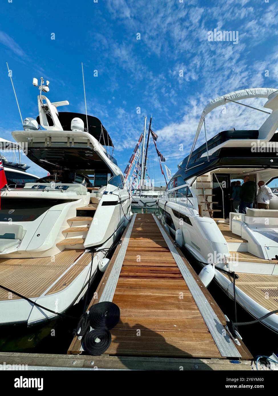 Low angle portrait image with head space looking between two moored motor cruisers on show at the Southampton International Boat Show. - Smartphone Captured Stock Image