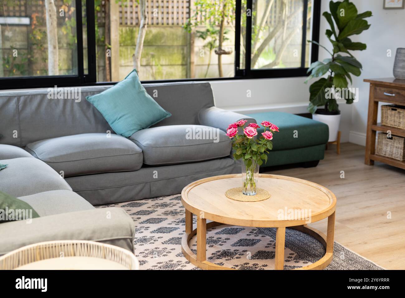 Living room with grey sofa and wooden coffee table with pink flowers in ...