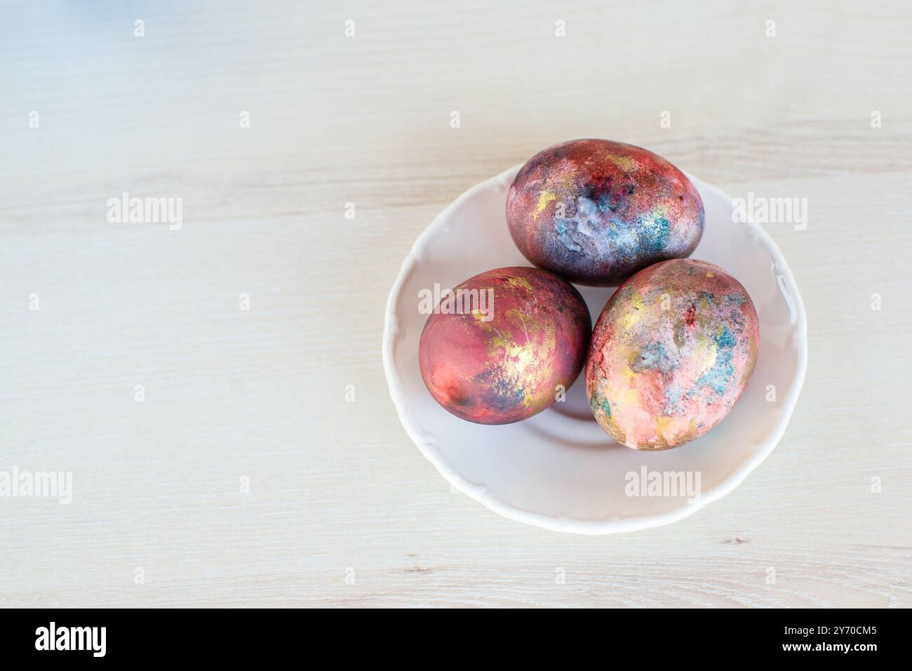Three Easter eggs painted in galaxy colors on the white plate Stock Photo