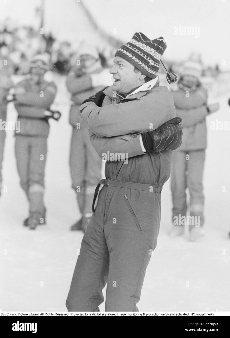 King Carl XVI Gustaf of Sweden. Born April 30, 1946. In Storlien in 1986 when he keeps warm and moves his body in a special way. A way to raise body temperature and increase blood circulation. One alternately extends the arms and then folds them around the upper body. The method originates from the era of horse-drawn carriages when frozen riders, i.e. carriage drivers, in the absence of a fire, kept warm in this way. Stock Photo