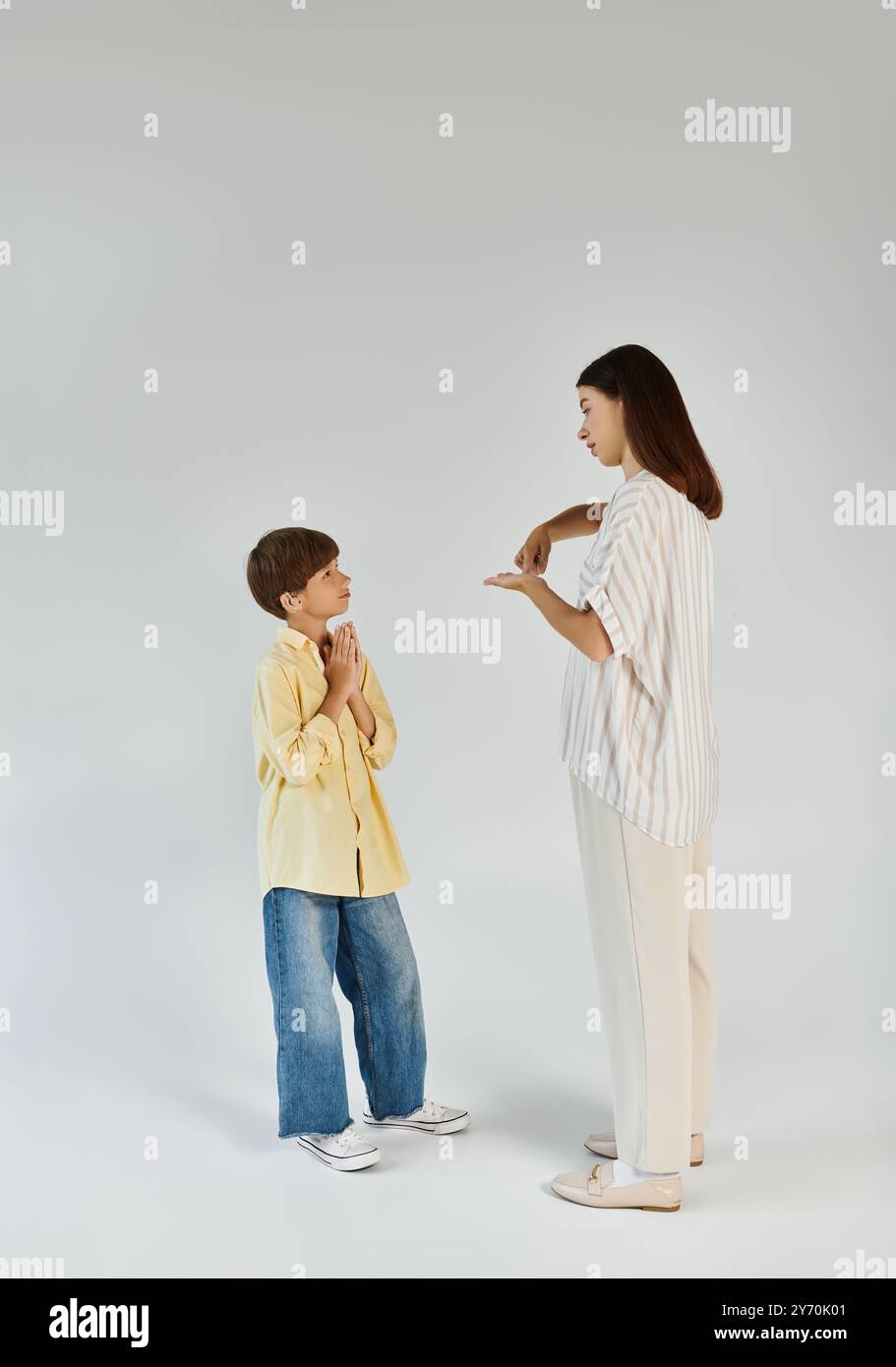 A caring mother engages with her hearing impaired son, fostering communication and connection. Stock Photo