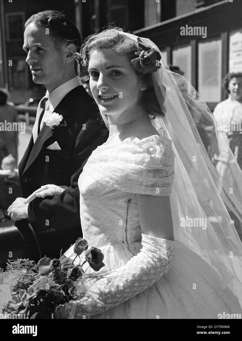 BRIDE ,18, HAD BOY , 16 , AS WEDDING DRESSMAKER   From a design chosen by the bright, 16-year-old Douglas Darnell of Kilburn (London) made the crinoline wedding dress in which Miss Patricia Bones, aged 18, of Barking, was married to Mr.L.Johnson of greys (Essex) at Caxton Hall register office, London,. The off- the- shoulder gown studded with mother- of- pearl sequins was made entirely by the boy.    PICTURE SHOWS:- The smiling bride leaving Caxton Hall with her bridegroom after the wedding.    July 8 1949 Stock Photo