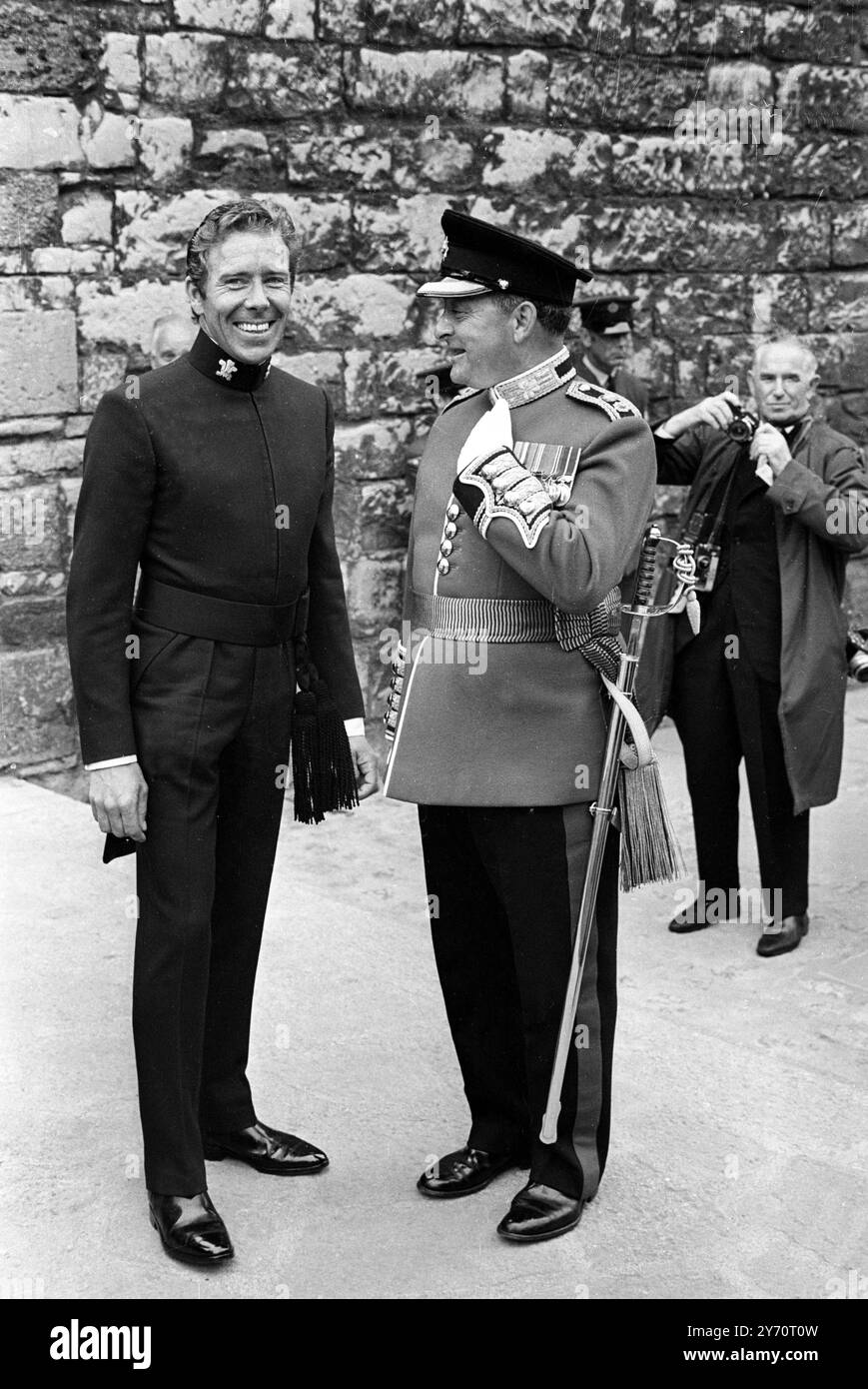 Caernarvon , Wales :  Even the usually gaily-dressed Lord Snowdon is in full uniform for this afternoons , investiture ceremony .  Dressed in the full regalia of Constable of Caernavon Castle he talks with Colonel C H Jaeger as he watches guests arrive from the Investiture of the Prince of Wales .  Two features of the Earl 's uniform are the morning style tail from his jacket and two tassels hanging from the side of his wide belt .1 July 1969 Stock Photo