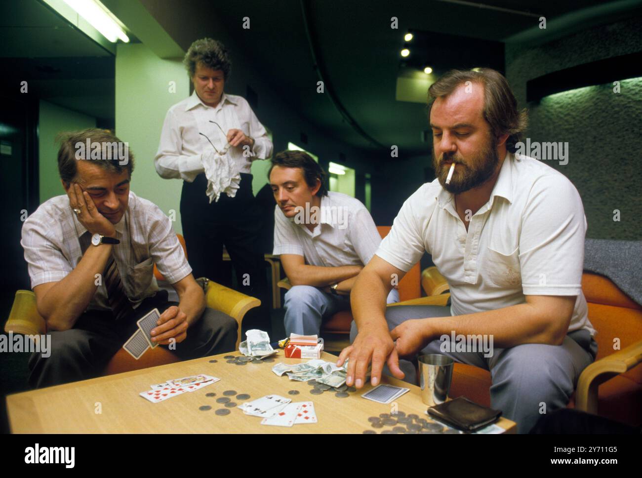 Playing a game of cards for money. Two men gambling, smoking and colleagues watching. Coins on table London England circa 1995 1990s UK HOMER SYKES Stock Photo