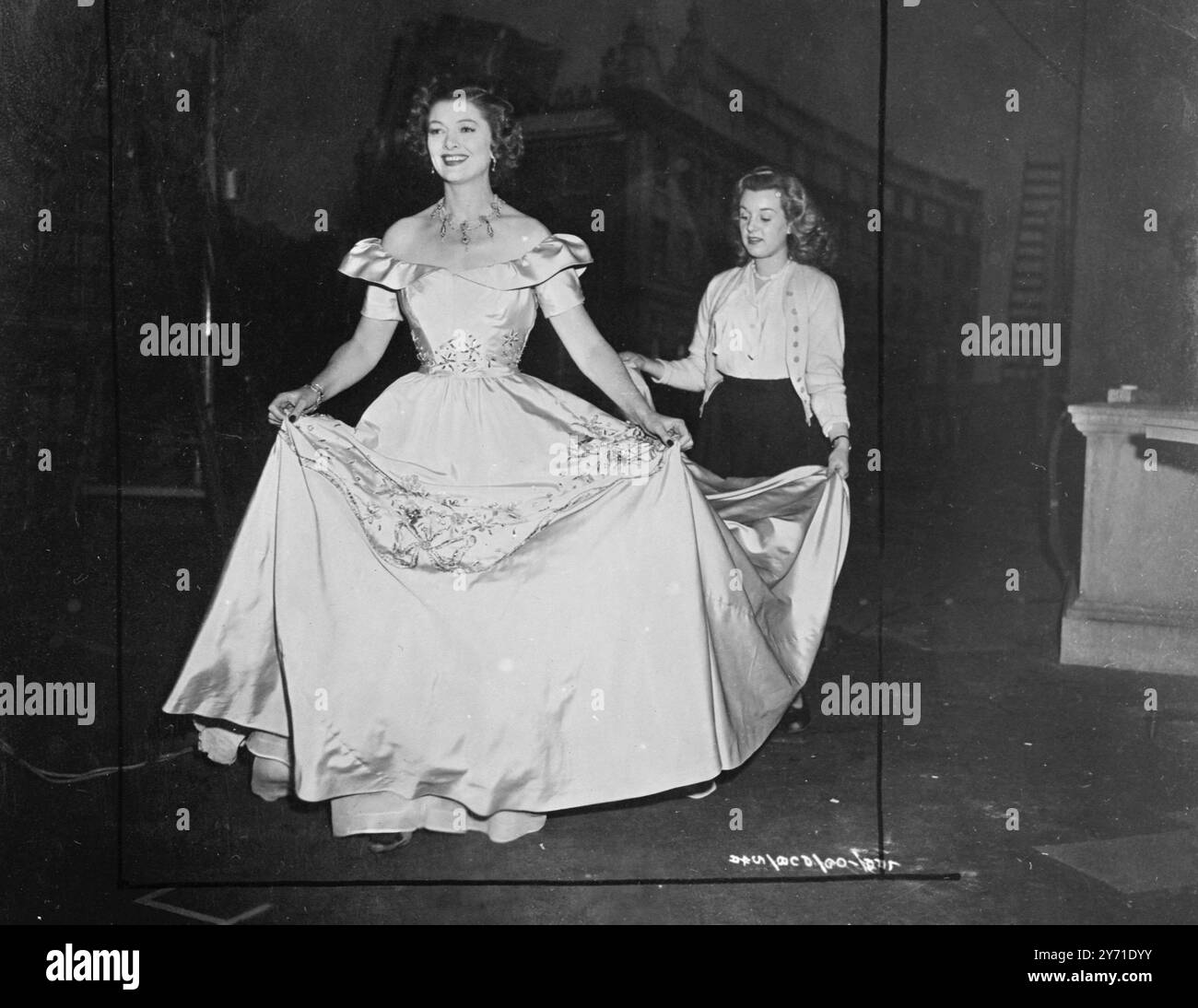 STAR PROGRESSMYRNA LOY, starring in 'The Case of Lady Brooke', has been called from her dressing-room to the stage for a shot. She is wearing a very full evening gown for a STAR PROGRESSMYRNA LOY, starring in 'The Case of Lady Brooke', has been called from her dressing-room to the stage for a shot. She is wearing a very full evening gown for a
