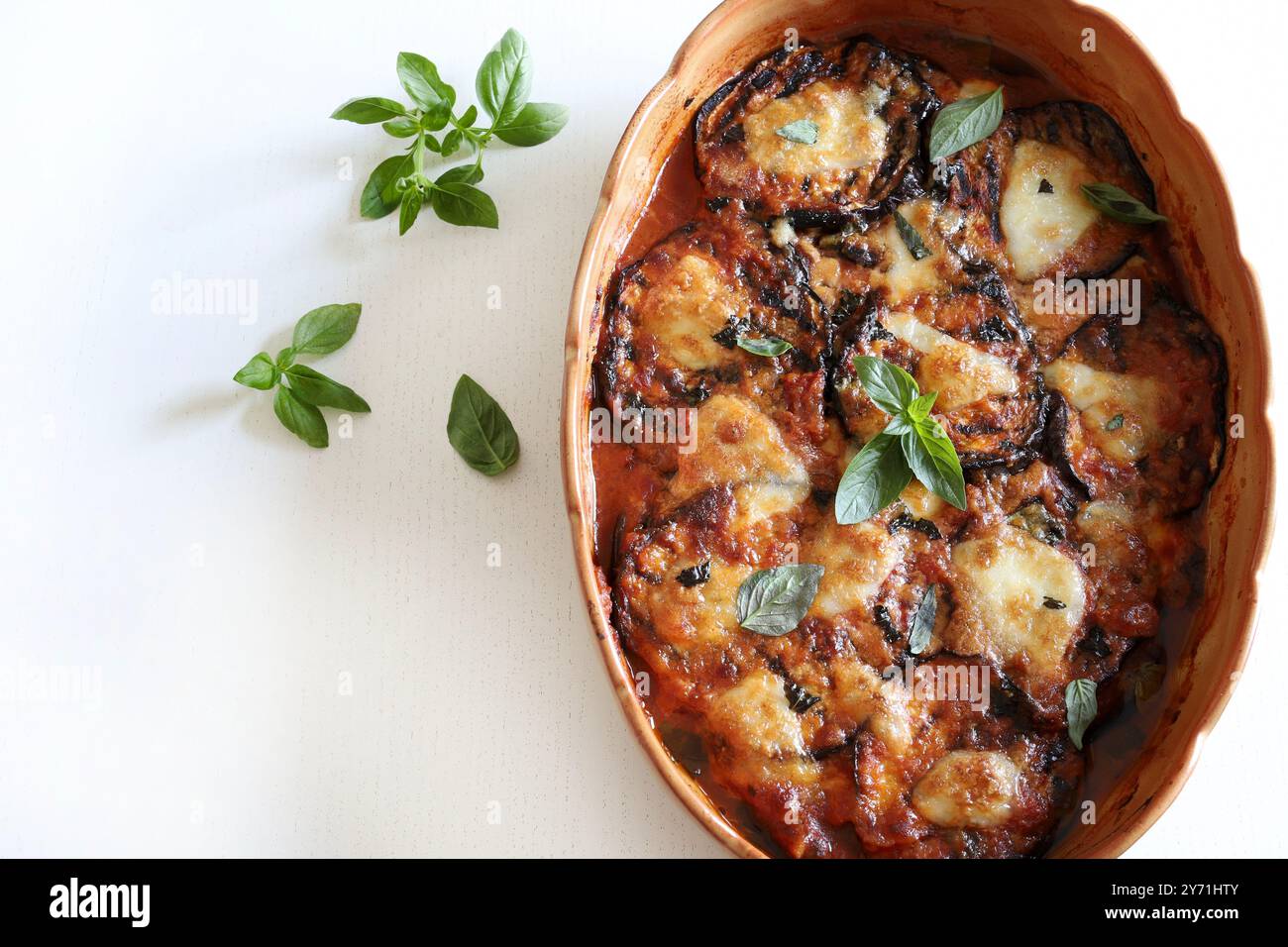 Baked aubergine parmigiana. Dish based on aubergines, tomato puree, fresh basil leaves, garlic, parmesan and mozzarella. Italian food. Directly above. Stock Photo