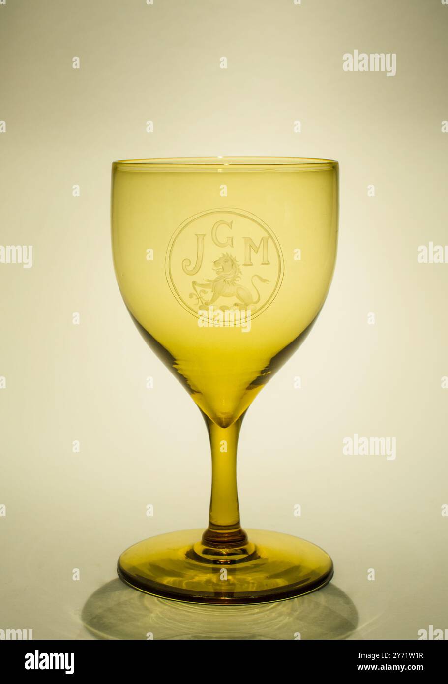Late Victorian Wine glass in Dark Amber with superbly copper wheel engraved Monogram and Lion Crest - Hand blown craftsmanship Stock Photo