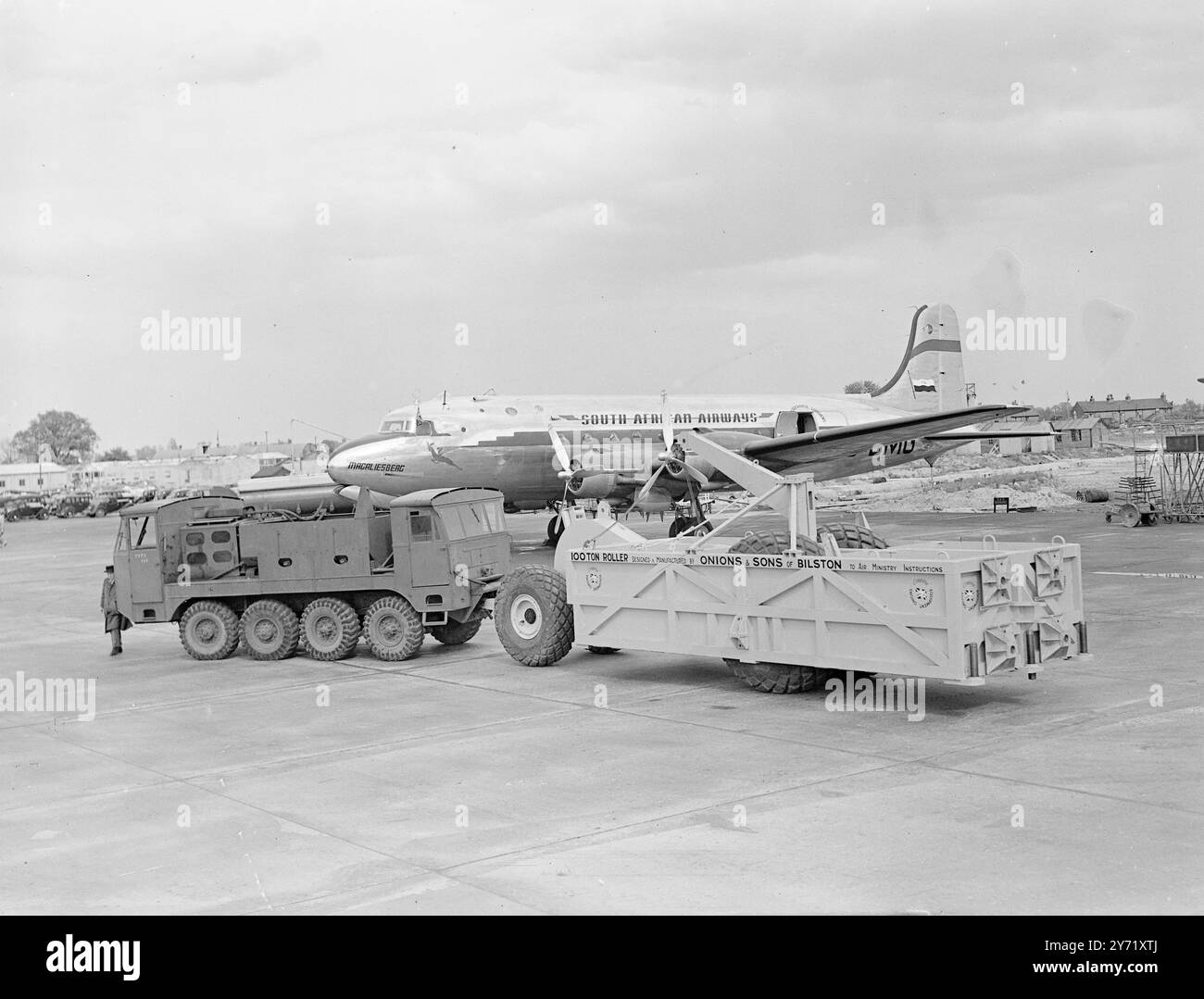 TESTING THE BOMBS Something new in modern machinery made its appearance at  London Airport in the shape of a large machine which will test runways by reproducing the landing of the heaviest aircraft .  Built to Air Ministry specifications , the machine is about 30 feet long and eight feet high , with pneumatic tyres 8' 6' in diameter . A 300 horse power tractor is used to tow the machine to its location .  PICTURE SHOWS: The roller machine ,  which can be loaded to a weight of 100 tons pressure on the wheels ,  being towed by 300 hp tractor at London Airport today . In the background is an air Stock Photo