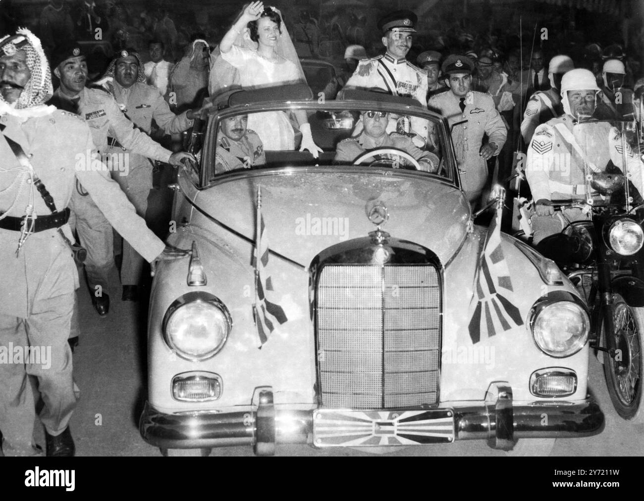 King Hussein and his British bride . Amman , Jordan :  King Hussein of Jordan and his new bride , formerly Miss Toni Gardiner of Ipswich , England , are seen in the Royal car during their drive through here after their wedding .  The couple were married in a hilltop Palace overlooking Amman , Jordan ' s capital , and in the streets 250,000 people roared approval , whistled , and danced until their stamping feet sent a haze of white dust mushrooming over the city .  Last night Amman was still dancing and there are five more days of festivities to come.  25 May , 1961 Stock Photo