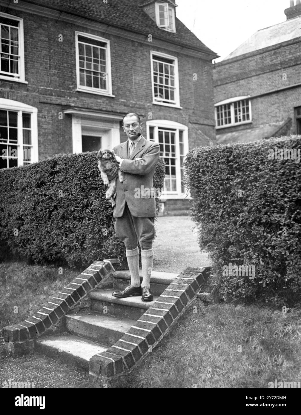 Sir Humphrey de Trafford, with Phoo, his peke, photographed on the steps leaading from the house to the swimming pool.Taken at his home at Newells Park, Barkway, Royston, Herts. 22 February 1946 Stock Photo