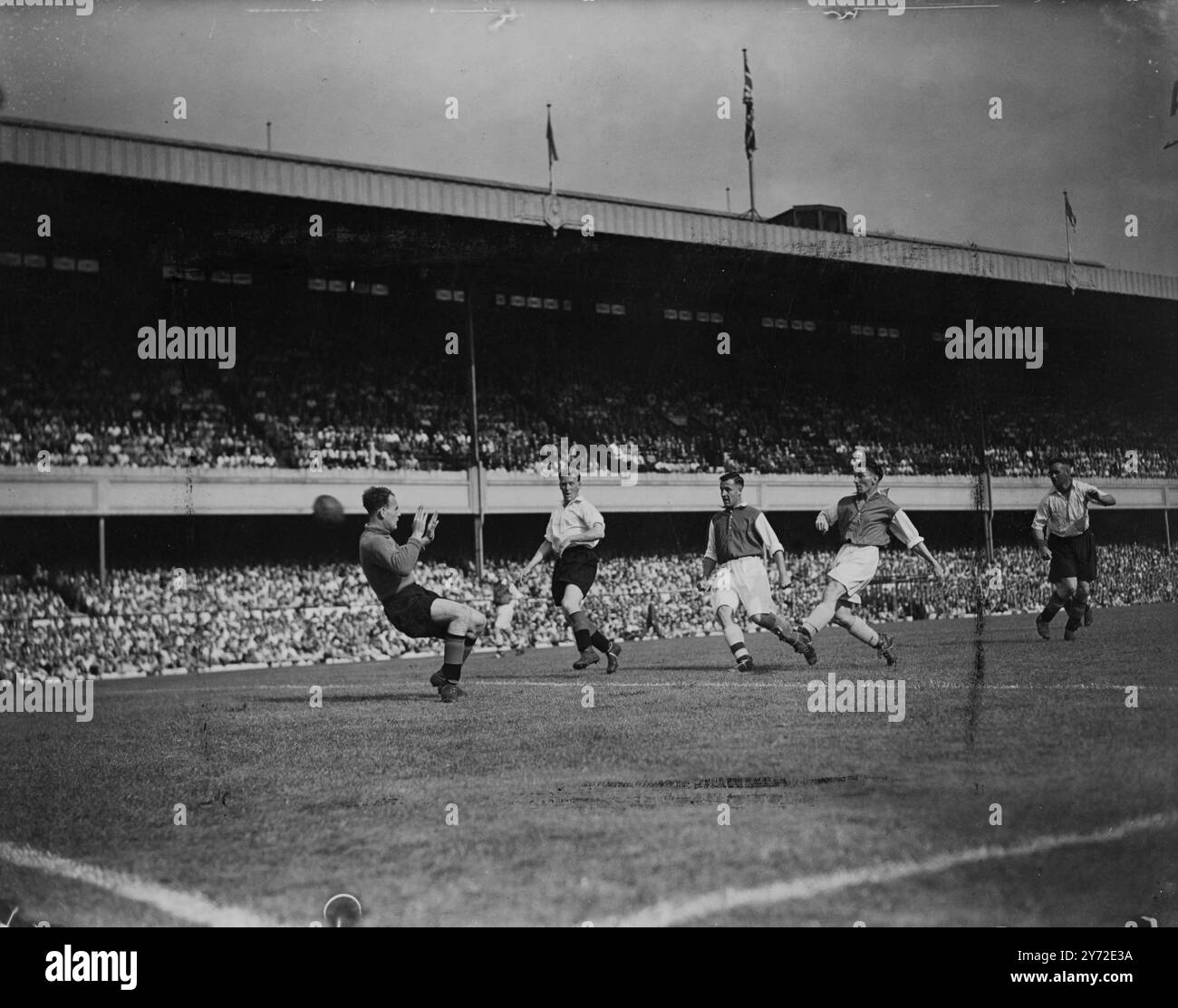One million soccer fans welcomed the opening of the season when a full table of matches was played in all departments of the English and Scottish Leagues. Highbury Stadium was packed with spectators eager to see the Arsenal open the season against Sunderland, with Roper, £11,000 right-winger from Southampton, and £10,000 Macaulay right half from Brentford, making their first appearance for the London side. Picture shows: Logie, the Arsenal inside-right (extreme right), puts the ball past goalkeeper Mapson to score Arsenal's second goal - an incident from Highbury this afternoon.  23 August 194 Stock Photo