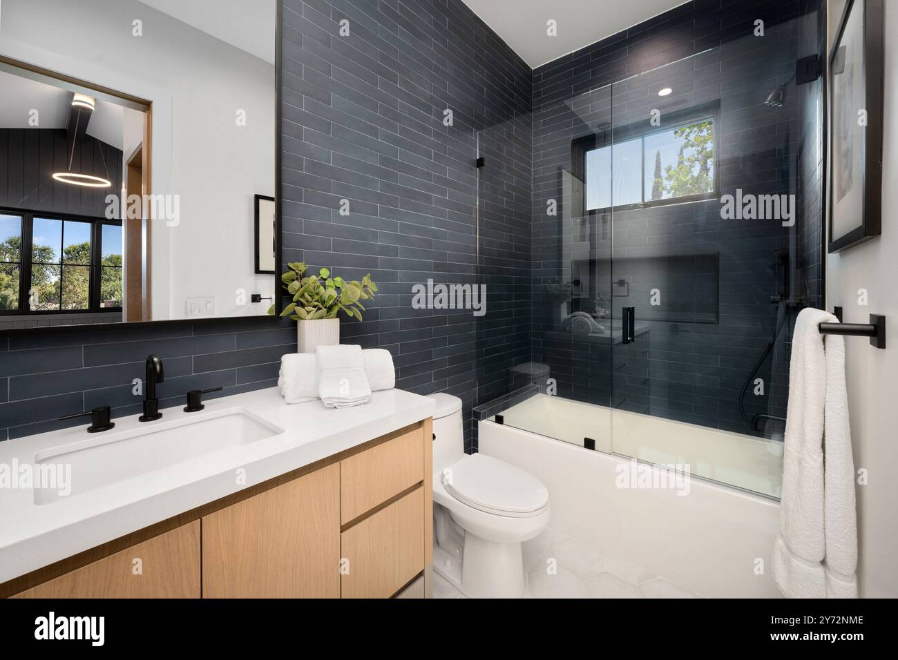 Modern bathroom with black tile walls, glass shower door, and wooden ...