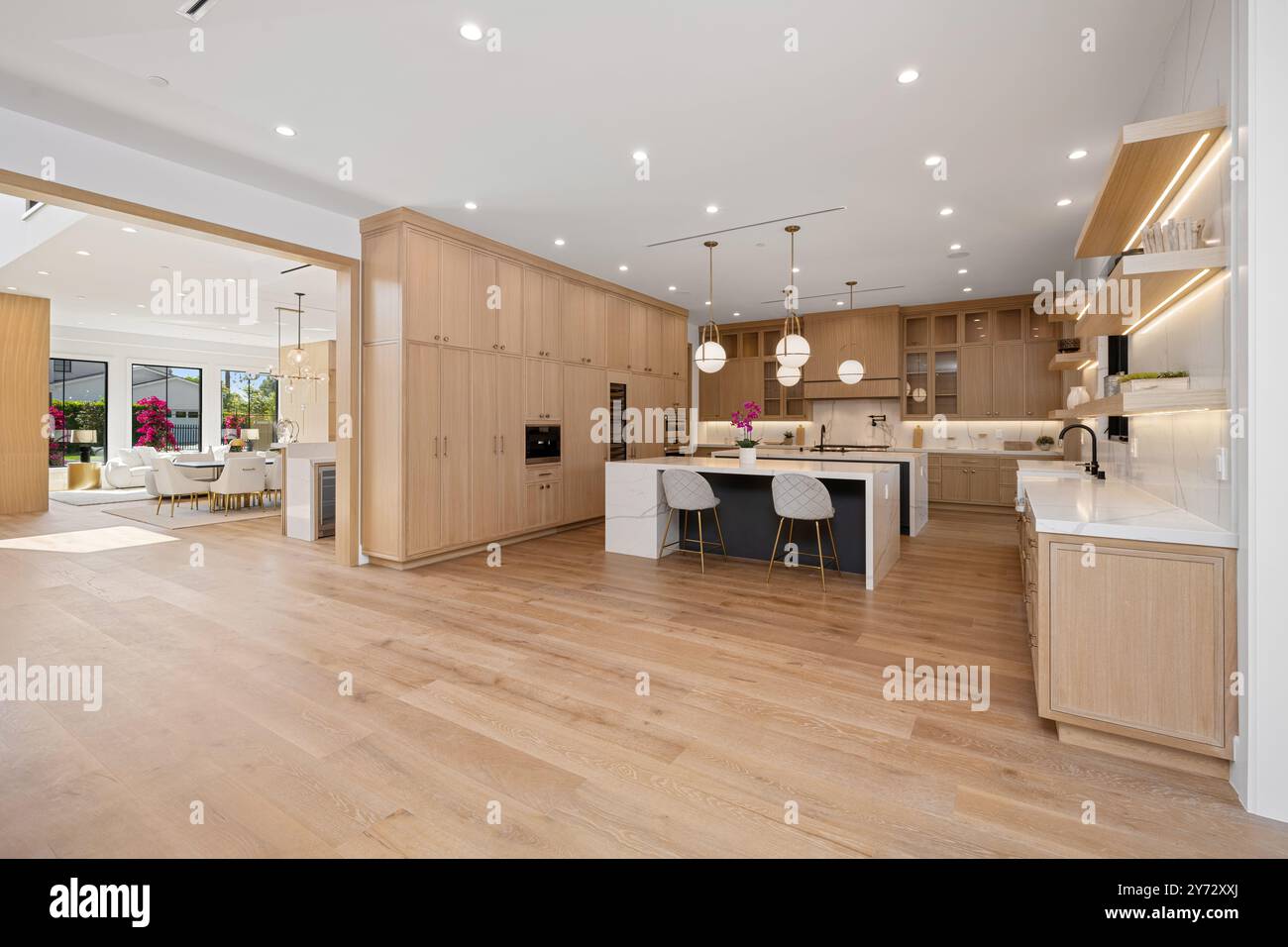 Modern luxury kitchen with light wood cabinetry, large island, and open ...