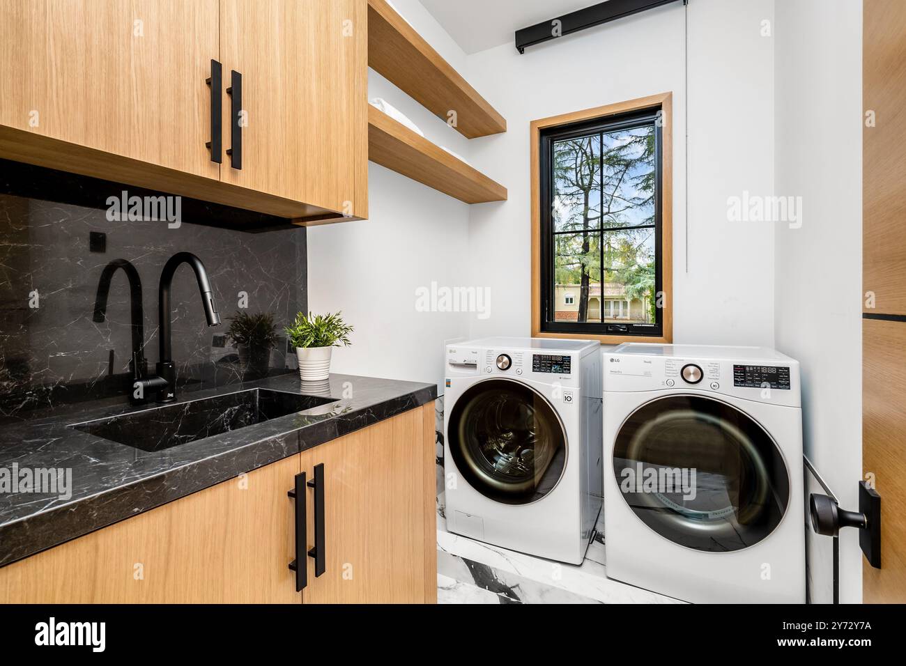 Modern laundry room with wooden cabinets, black countertop, and front ...