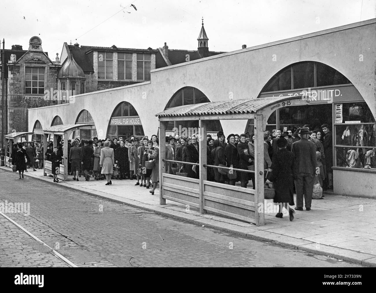 With Plymouth shopping centre completely demolished during the Blitz, the opening of the first post-war shops attracted crowds of eager shoppers. These new shops are converted Nissen huts with a concrete facade for the whole frontage. Picture shows long queues await the opening of the first shops.  7 May 1946 Stock Photo