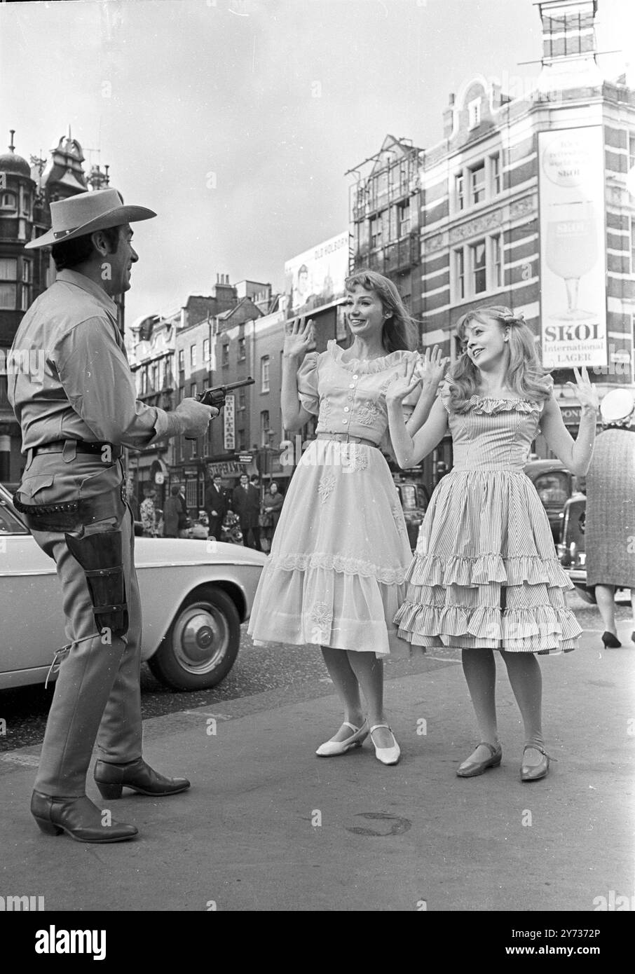 Singer Ivor Emmanuel during a mock hold-up of actresses Inga Swenson (centre) and Vanessa Howard outside  London's Palace Theatre today, January 31. All three are among the principals of '110 In the Shade', - an American musical opening at theatre February 8, with a full company of 47.  31 January 1967 Stock Photo