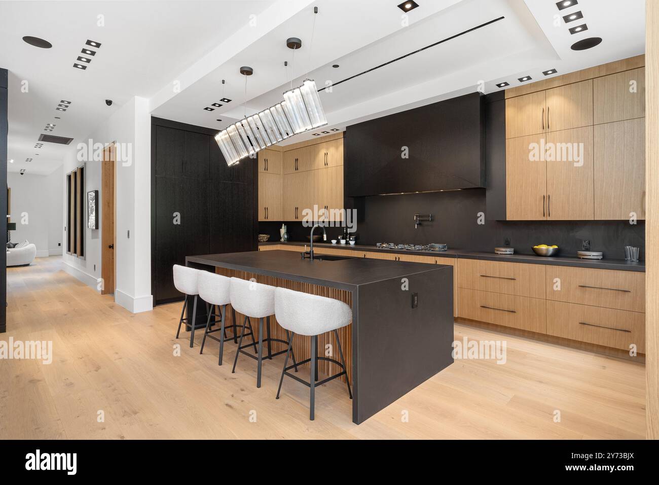 Modern kitchen interior with wooden cabinets, black countertops, and a ...