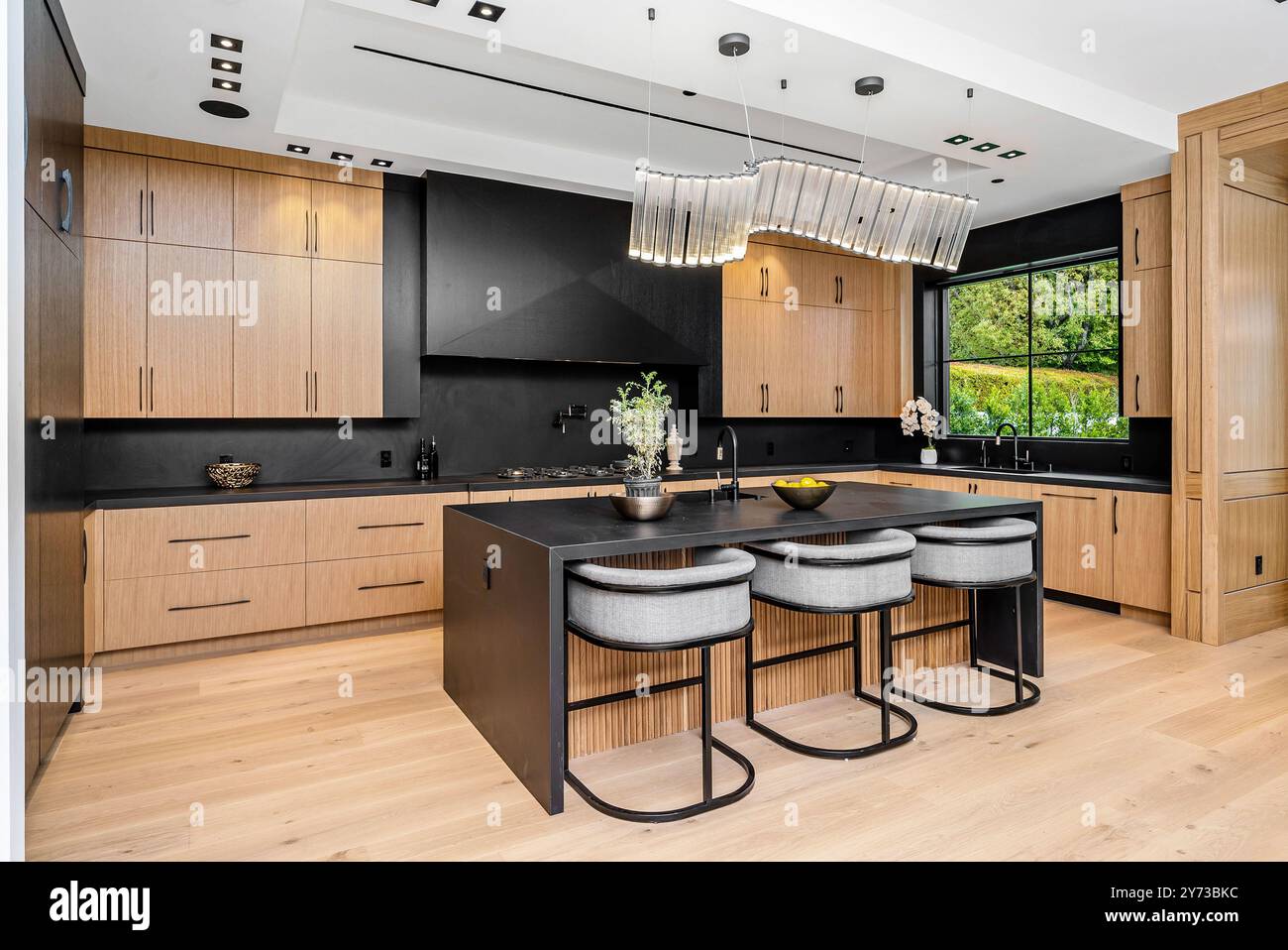 A modern kitchen featuring wooden cabinets and sleek black countertops ...