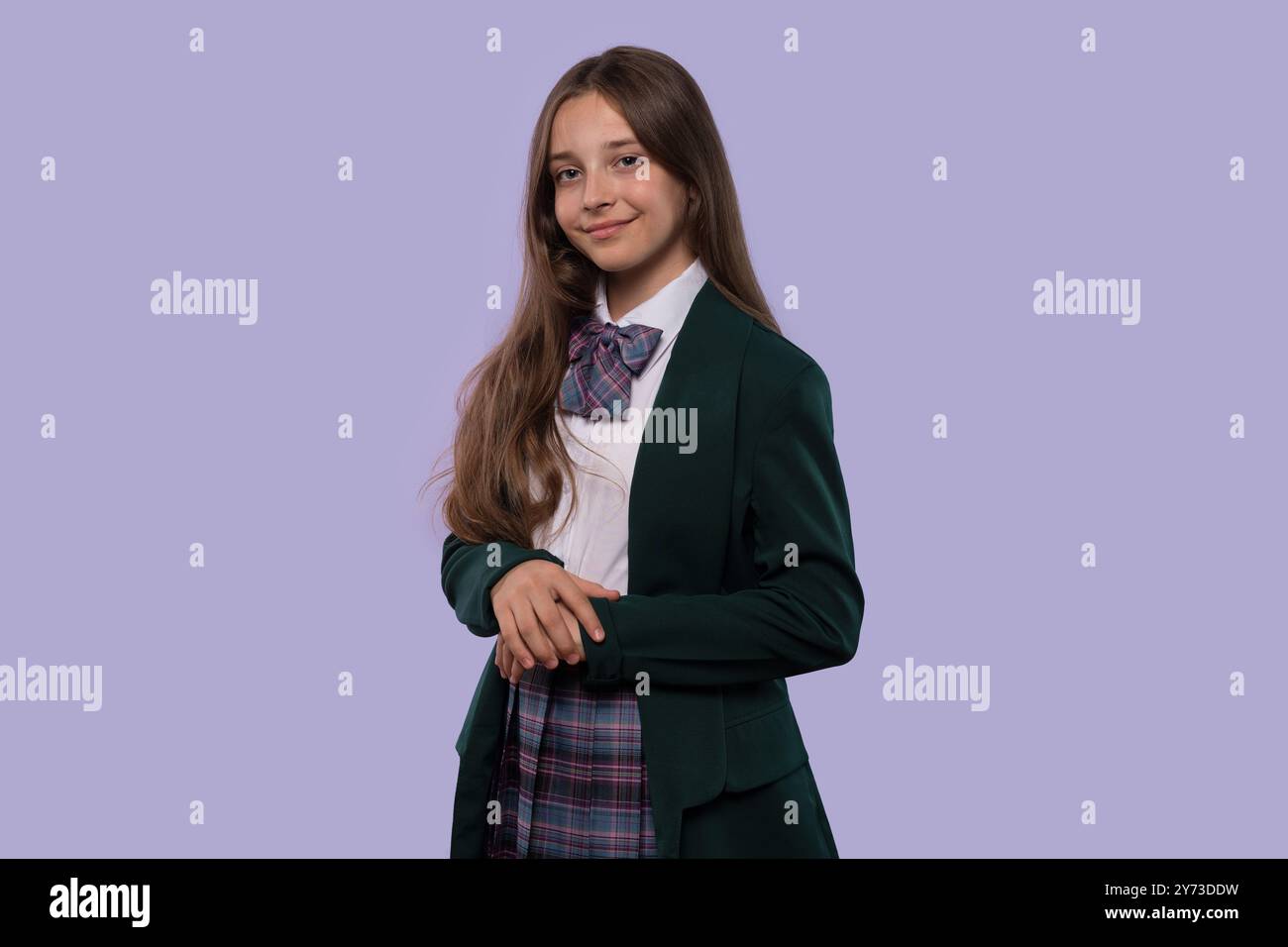 A young girl in a green school uniform posing confidently against a ...