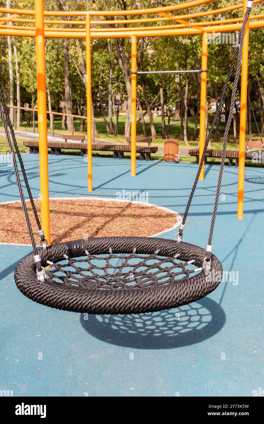 a safe swing made of ropes and tires without metal parts on a modern playground. a sunny day Stock Photo