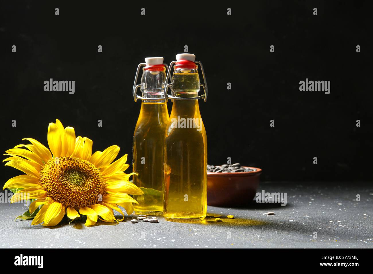 Bottles of sunflower oil and bowl with seeds on black background Stock ...