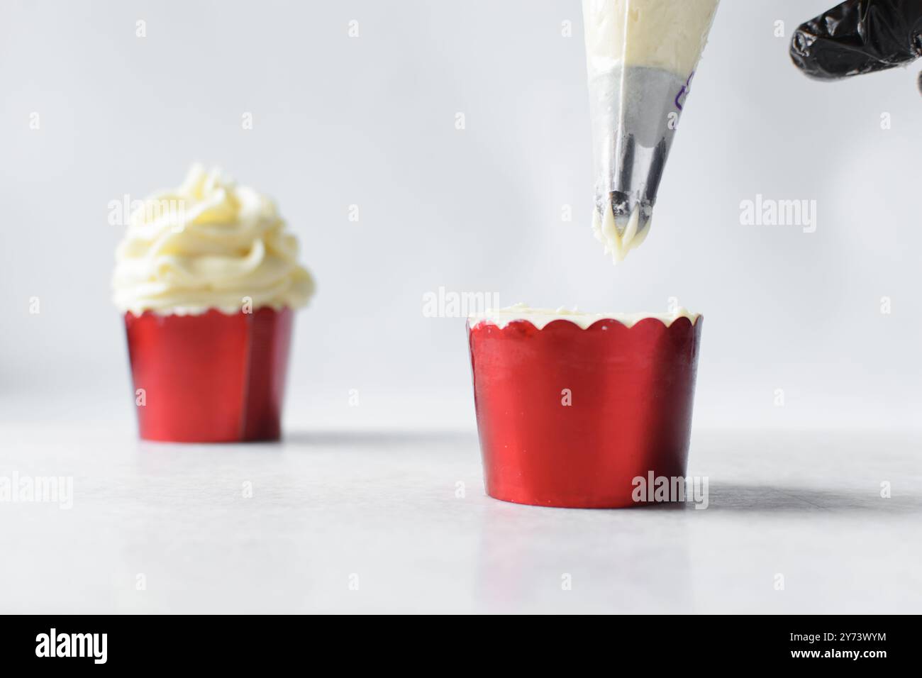 Piping buttercream on a cupcake, decorating cupcakes, hand piping tall frosting on cupcakes, the process of decorating cupcake Stock Photo
