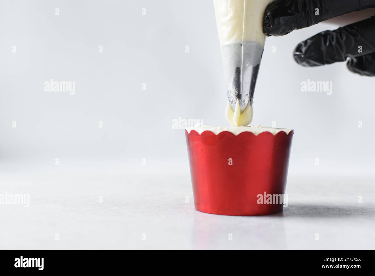 Piping buttercream on a cupcake, decorating cupcakes, hand piping tall frosting on cupcakes, the process of decorating cupcake Stock Photo