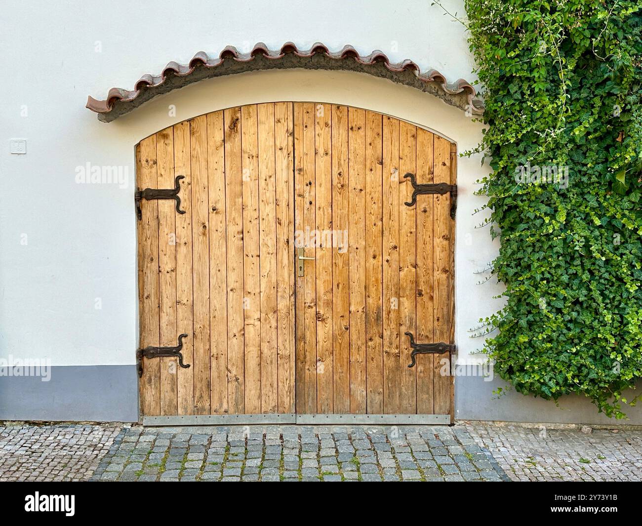 The photograph captures a detailed view of an old medieval gate made of wood and metal, set in the streets of a historic European city. - Smartphone Captured Stock Image