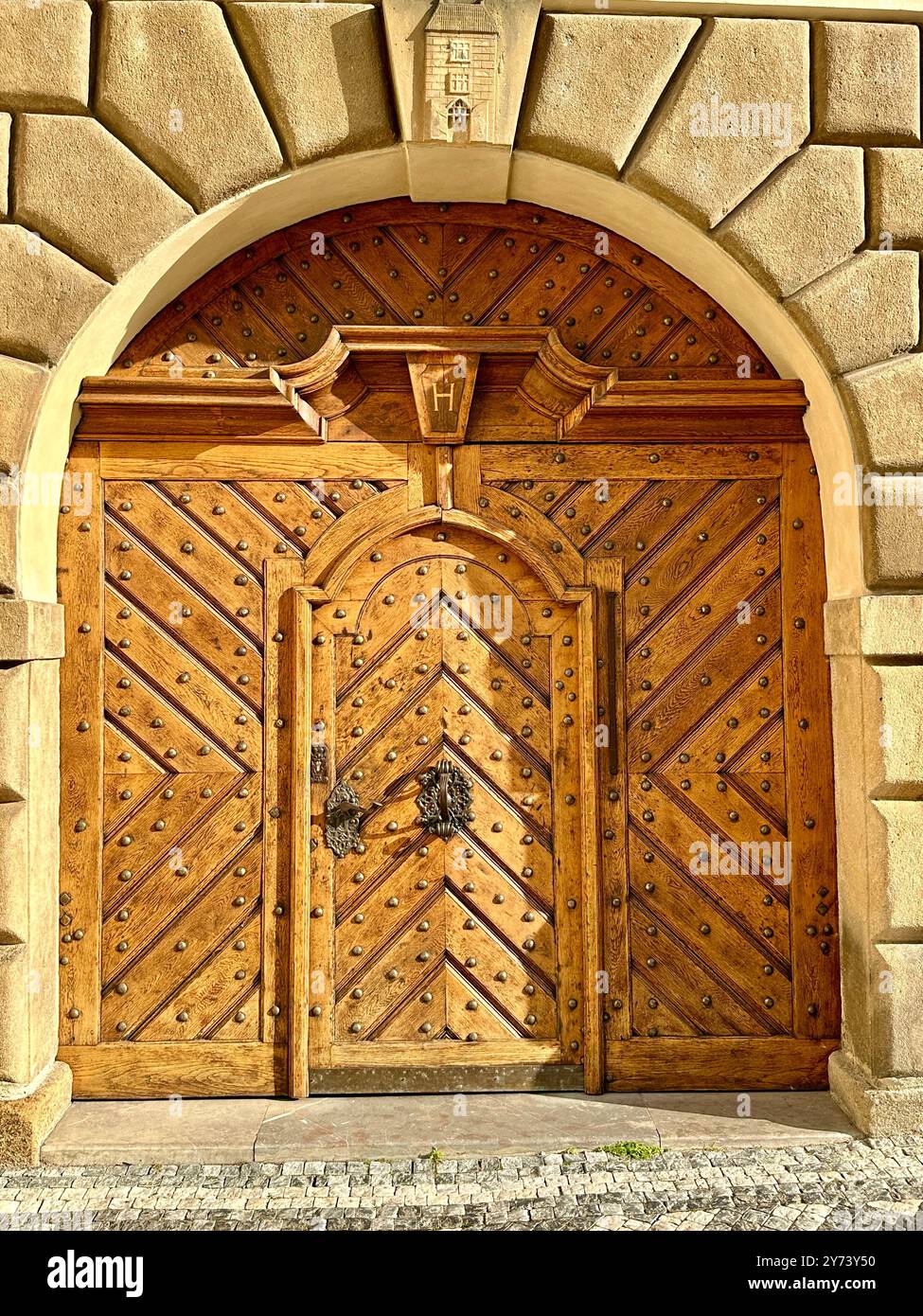 The photograph captures a detailed view of an old medieval gate made of wood and metal, set in the streets of a historic European city. - Smartphone Captured Stock Image