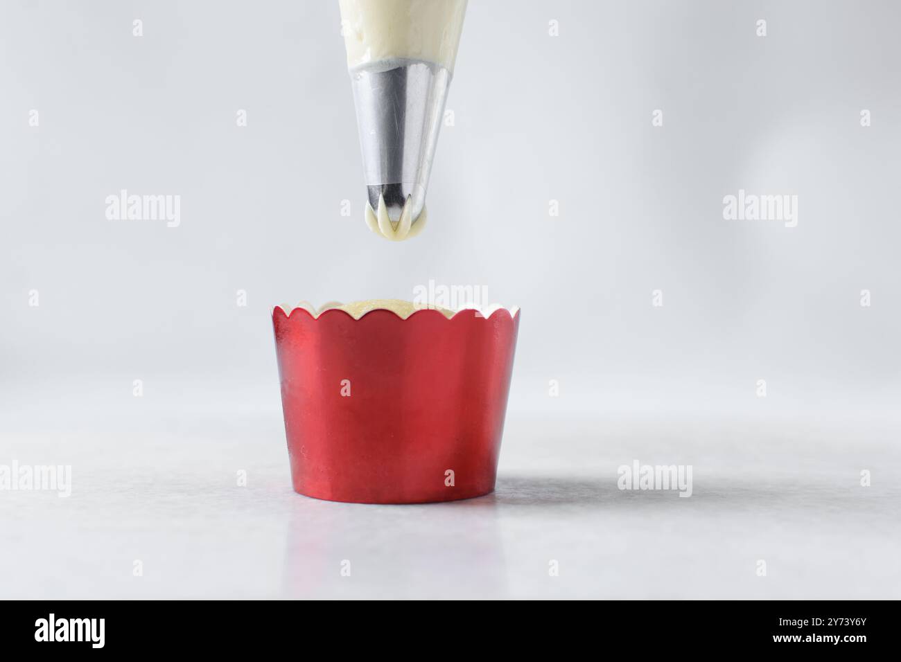 Piping buttercream on a cupcake, decorating cupcakes, hand piping tall frosting on cupcakes, the process of decorating cupcake Stock Photo