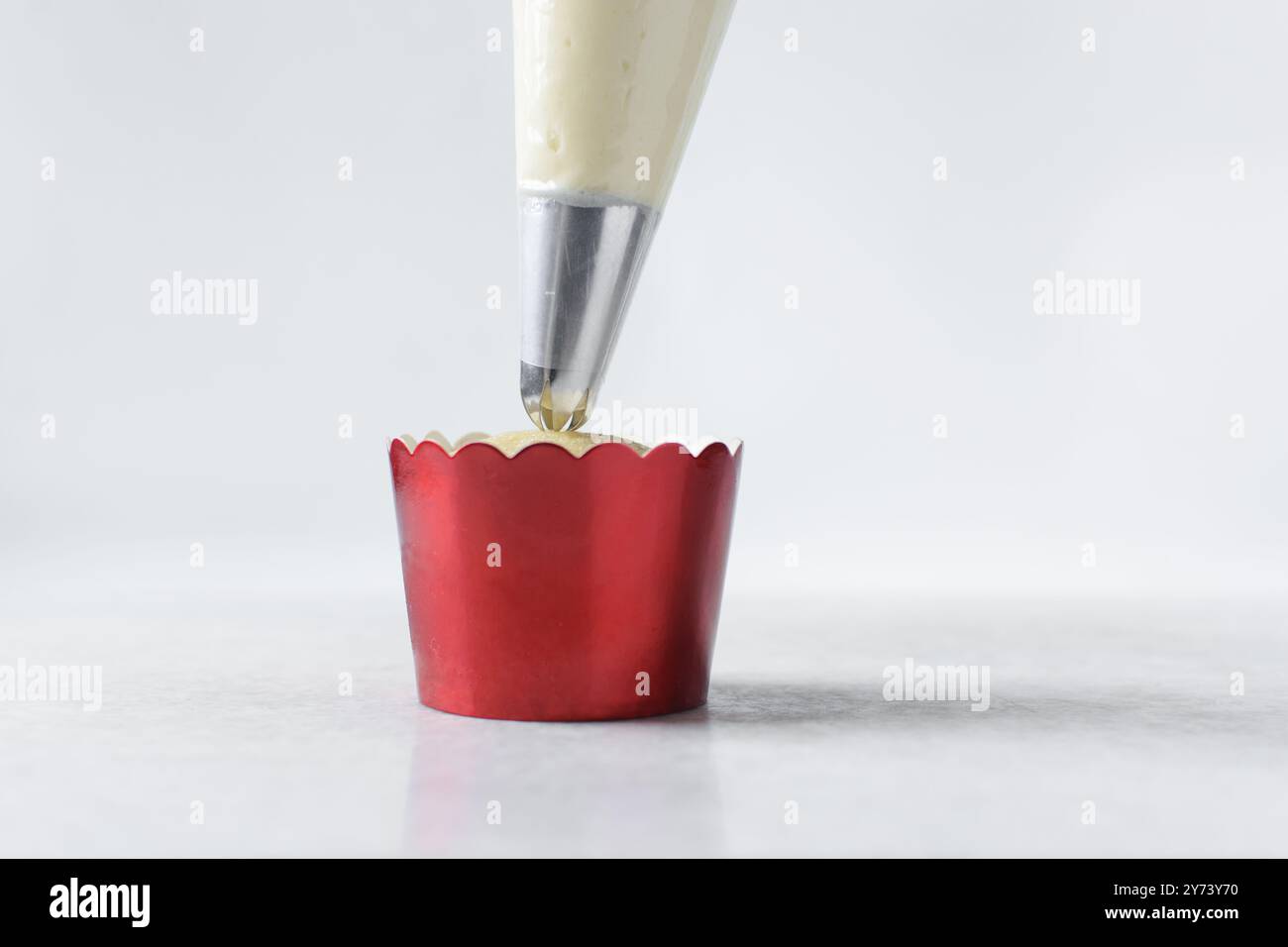 Piping buttercream on a cupcake, decorating cupcakes, hand piping tall frosting on cupcakes, the process of decorating cupcake Stock Photo