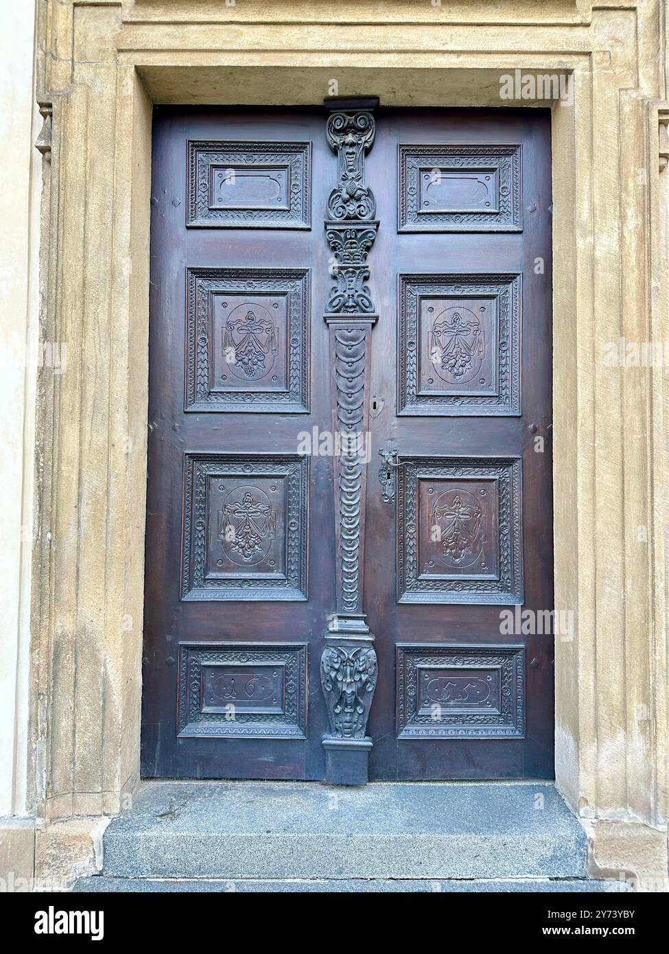 The photograph captures a detailed view of an old medieval gate made of wood and metal, set in the streets of a historic European city. - Smartphone Captured Stock Image