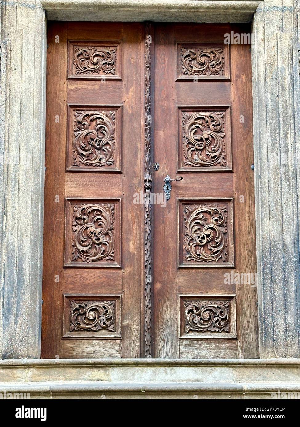 The photograph captures a detailed view of an old medieval gate made of wood and metal, set in the streets of a historic European city. - Smartphone Captured Stock Image
